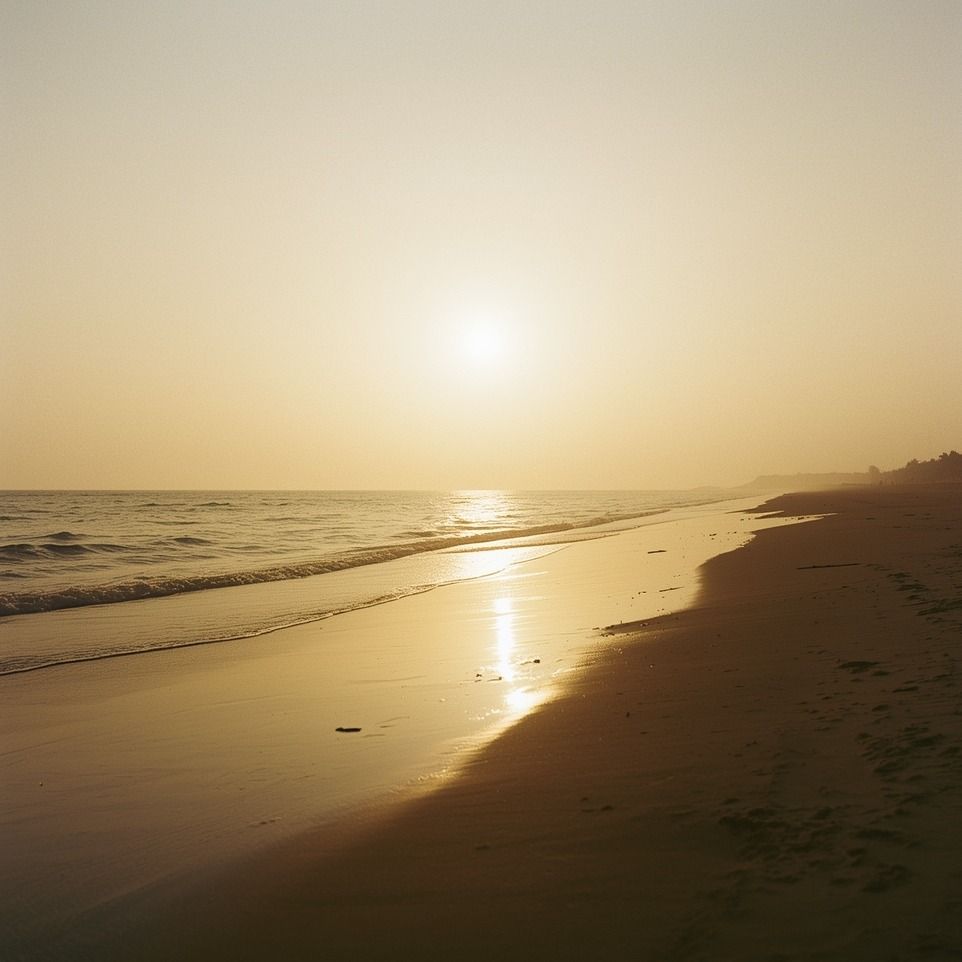 Praia em luz dourada, com o sol baixo refletido na areia (imagem ilustrativa)